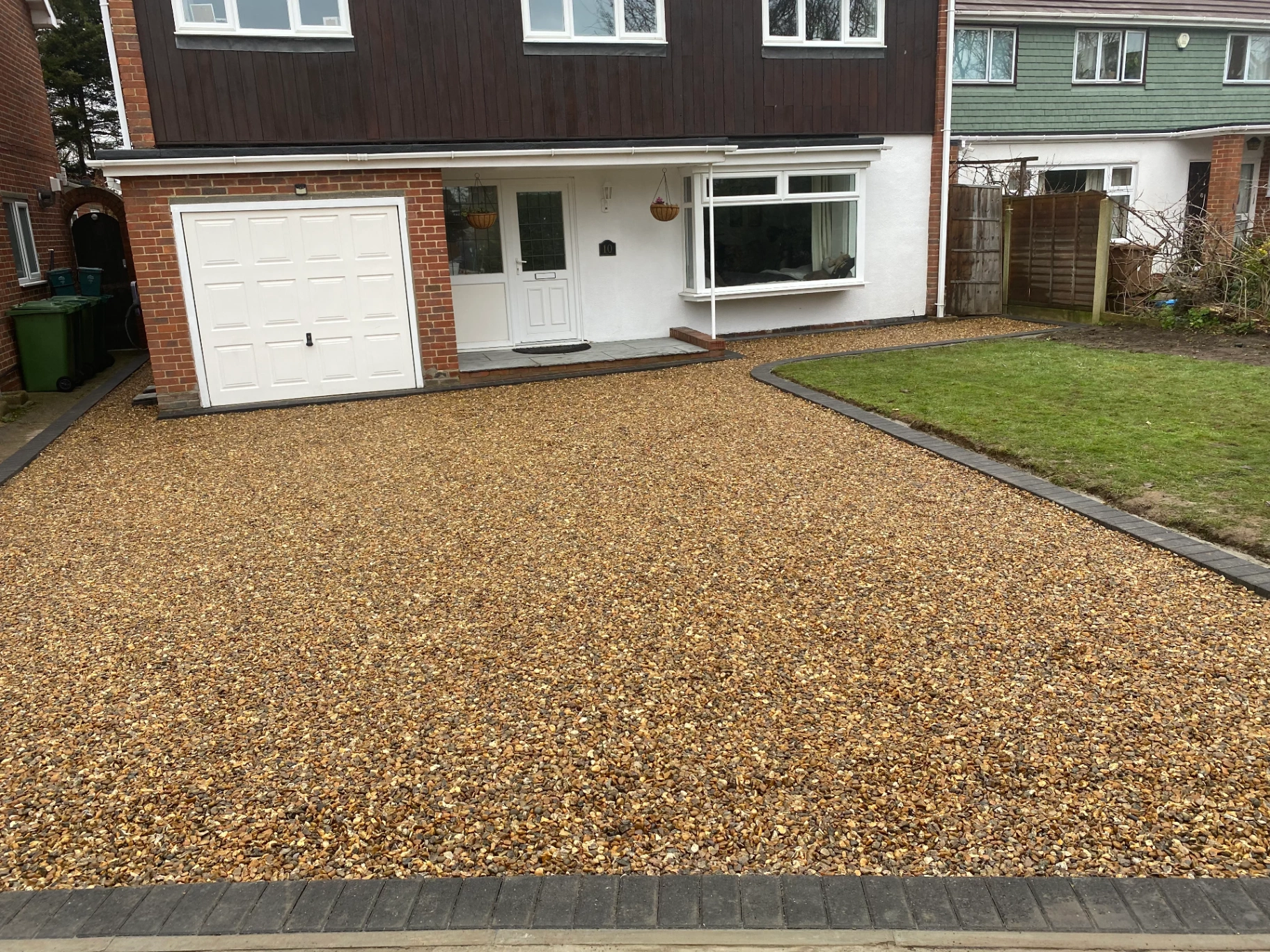Golden gravel driveway with charcoal block border to a semi-detached home